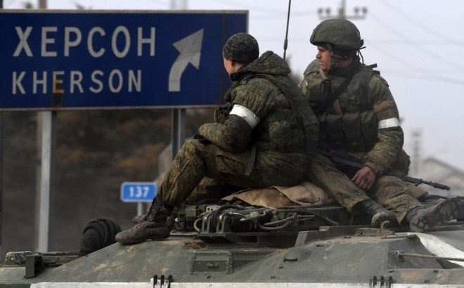 Binh sĩ Nga trên xe thiết giáp cạnh biển chỉ đường về phía thành phố Kherson. Ảnh: Reuters