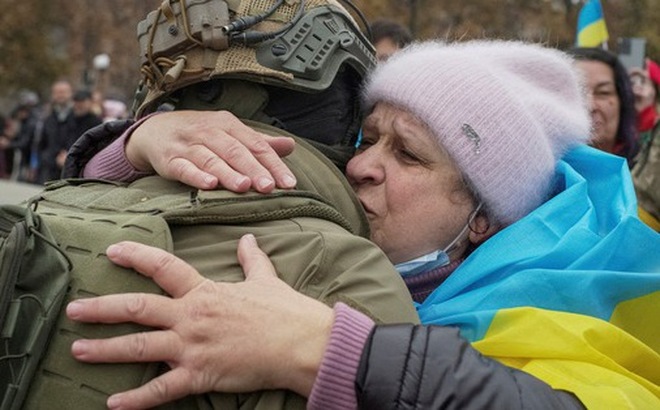 Người dân địa phương ôm một quân nhân Ukraine ở thành phố Kherson, Ukraine vào ngày 12-11 - Ảnh: REUTERS