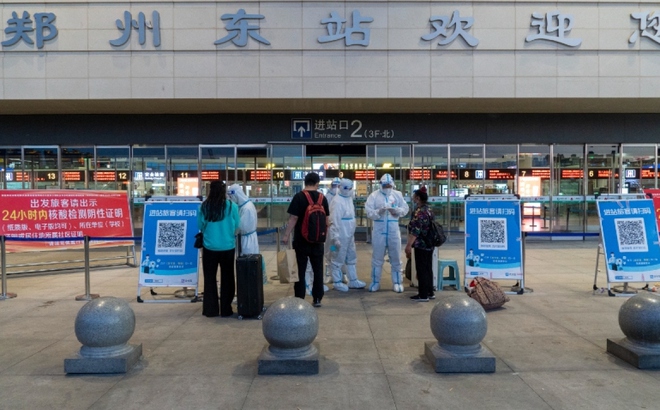 Nhân viên chống dịch kiểm tra mã sức khỏe của du khách tại ga xe lửa Đông Trịnh Châu. Ảnh: VCG