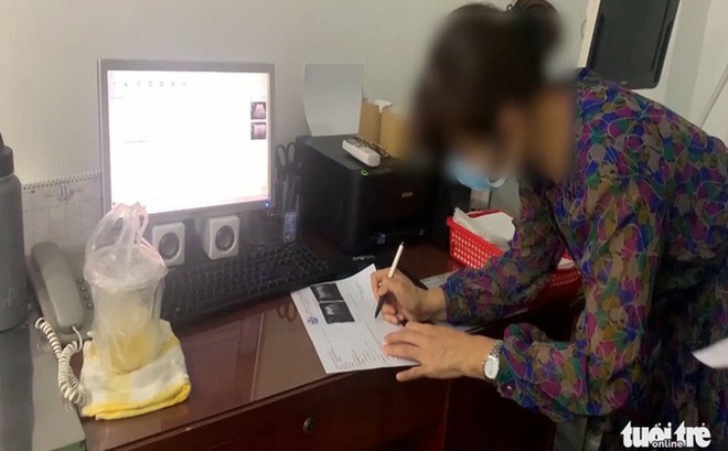 Bác sĩ người Việt in và ký trả kết quả siêu âm cho người bệnh trong một phòng khám tư có yếu tố nước ngoài. Thời điểm Thanh tra Sở Y tế kiểm tra tháng 11-2022, bác sĩ này không mặc trang phục nhân viên y tế và không đeo bảng tên - Ảnh: V.E.
