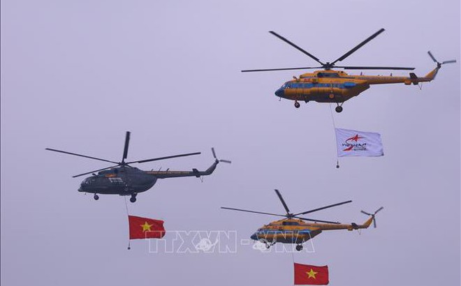 Biên đội trực thăng dòng Mi thuộc Trung đoàn không quân 916 cùng cờ Tổ quốc và cờ hiệu Triển lãm Quân sự quốc tế Việt Nam 2022 biểu diễn trên không gian triển lãm. Ảnh: Văn Điệp/TTXVN