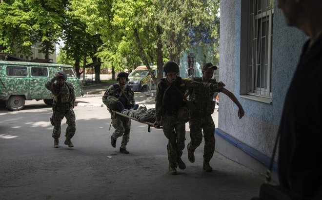 Các binh sỹ Ukraine đang khiêng một người lính bị thương sau một cuộc tấn công tại Donetsk. Ảnh: AP