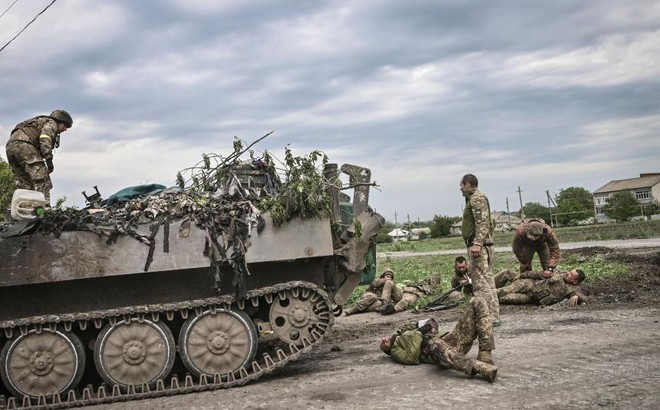Các quân nhân Ukraine hỗ trợ đồng đội của họ không xa chiến tuyến, ở vùng Donbass, miền Đông Ukraine, ngày 21/5/2022. Ảnh: Straits Times