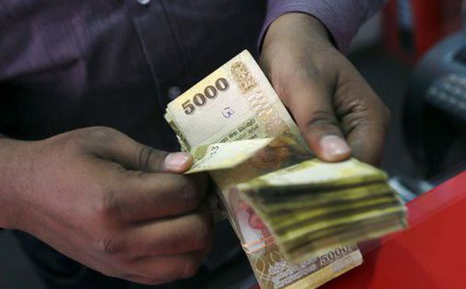 Một người đàn ông đếm tiền rupee Sri Lanka tại quần đổi tiền ở Colombo - Ảnh: REUTERS