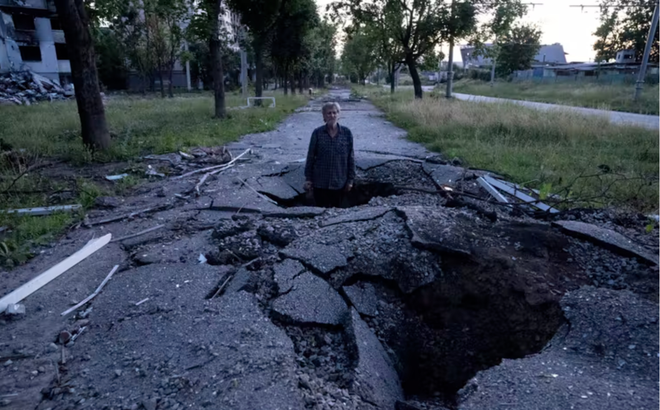 Một người đứng trong miệng hố tên lửa ở Kharkiv, Ukraine, ngày 1/7/2022. Ảnh: AP