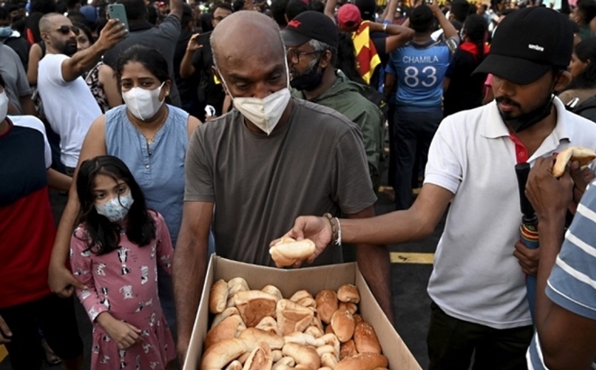 Phát bánh mỳ cho đám đông bên ngoài văn phòng Tổng thống Sri Lanka. (Ảnh: AFP)