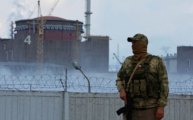 Một quân nhân với cờ Nga trên quân phục đứng gác gần nhà máy điện hạt nhân Zaporizhzhia. Ảnh: Reuters