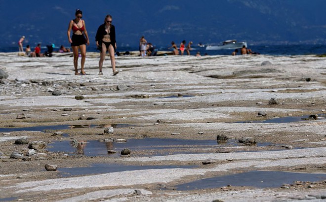 Người dân Italy đi bộ trong hồ Garda đã cạn trơ đáy. Ảnh: Reuters