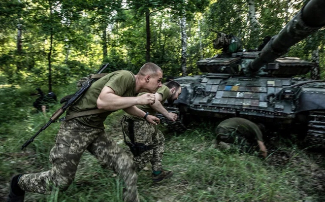 Lính Ukraine ẩn nấp sau xe tăng tránh đạn pháo. Ảnh: Levine.