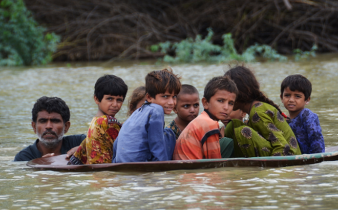 Người dân Pakistan băng qua nơi ngập nước do lũ lụt. Ảnh: AFP