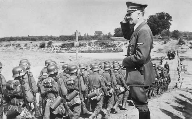 Hitler chào khi giám sát quân đội trong thời kỳ Đức quốc xã chiếm đóng Ba Lan. Quân nhân hành quân về phía một cây cầu gỗ do Đức quốc xã xây dựng bắc qua sông San, gần Jarolaw, Ba Lan - Ảnh: GETTY IMAGES