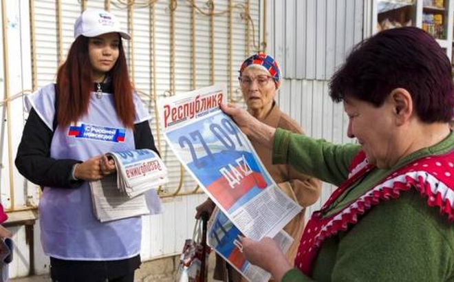 Một tình nguyện viên thuộc Ủy ban bầu cử khu vực Lugansk phát báo cho người dân địa phương ở khu vực này ngày 22/9/2022. Ảnh: APTN