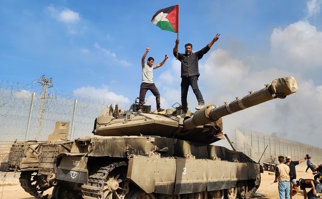 Người Palestine đứng trên một chiếc xe tăng của Israel bị phá hủy vào ngày 07/10. (Ảnh: Getty Images).