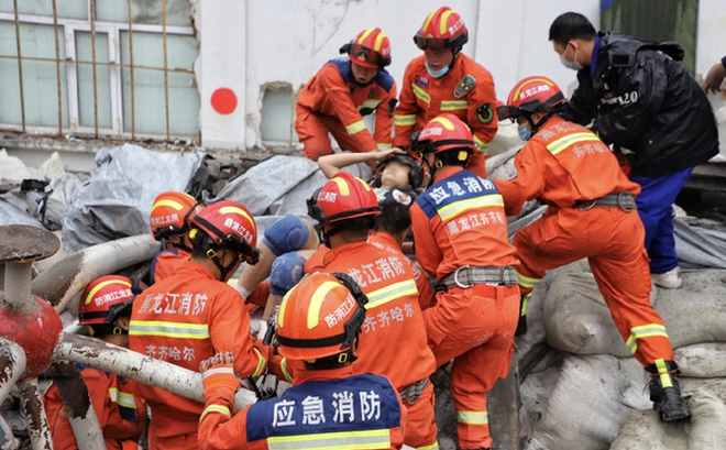 Nhân viên cứu hộ kéo một người bị mắc kẹt ra ngoài sau khi trần nhà thi đấu tại trường học sập ở thành phố Tề Tề Cáp Nhĩ, tỉnh Hắc Long Giang hôm 23/7. (Ảnh: Nhân dân nhật báo)