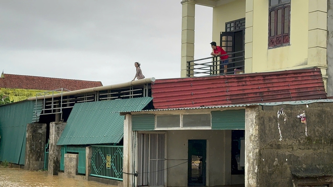 Nước lũ vây tứ phía, người dân Quảng Bình đứng trên nóc nhà nhận hàng cứu trợ - Ảnh 10.