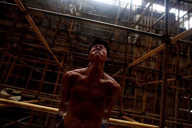 24h qua ảnh: Công nhân TQ lấy giàn giáo xây chùa làm xà đơn - Ảnh 2.
