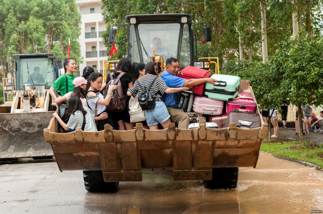 24h qua ảnh: Nhân viên cứu hộ cõng em bé trong mưa lũ - Ảnh 1.