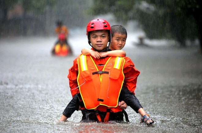 24h qua ảnh: Nhân viên cứu hộ cõng em bé trong mưa lũ - Ảnh 6.