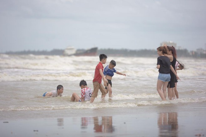 Bất chấp sóng to, gió lớn, nhiều người vẫn ra tắm ở biển Cửa Lò - Ảnh 1.