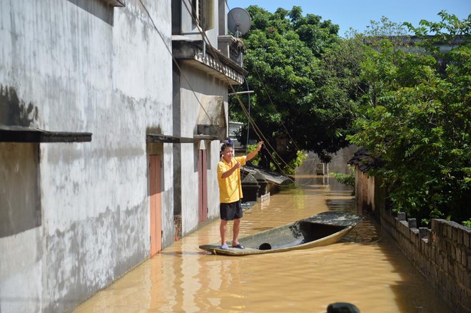 Chùm ảnh: Nhà ngập sâu đến ngang cửa, người dân Ninh Bình dùng chậu nhôm, ghế gỗ chèo thuyền đi lại trong ngõ - Ảnh 1.