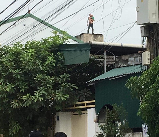 [NÓNG] Nam thanh niên xăm trổ ôm con leo lên nóc nhà 3 tầng, nhảy qua các mái nhà - Ảnh 2.