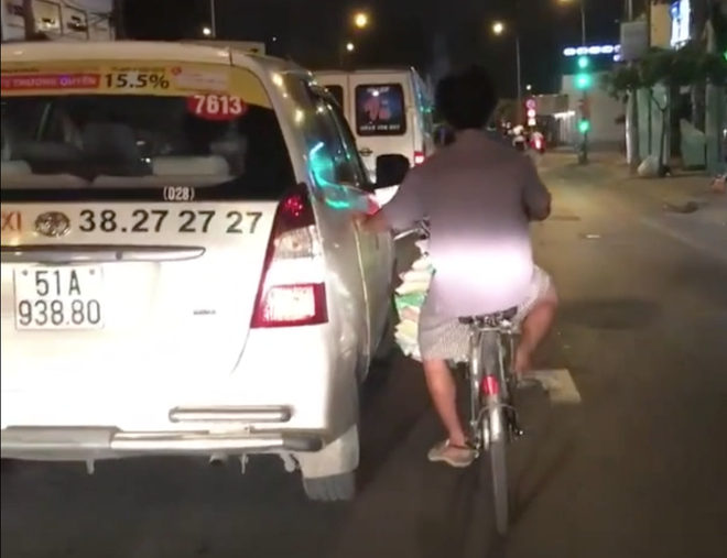 Tp.HCM: Người đàn ông thản nhiên bám xe taxi đi suốt một đoạn đường dài vì lười đạp xe - Ảnh 2.