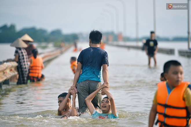 Chùm ảnh: Người lớn, trẻ nhỏ Hà Nội mặc áo phao ùa ra đường tỉnh lộ bơi lội, đánh cá sau nhiều ngày mưa ngập - Ảnh 8.