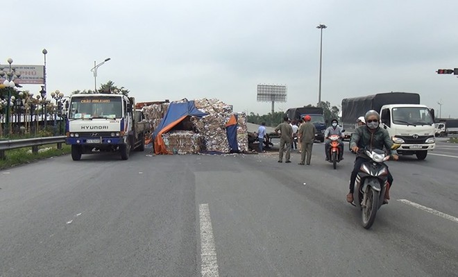 Lật xe đầu kéo, nhiều tấn giấy vụn đổ ra đường dẫn cao tốc - Ảnh 1.