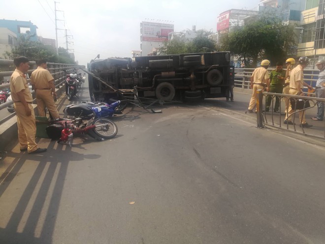 Xe tải lật trên cầu vượt trúng 2 xe máy ở Sài Gòn, ít nhất 3 người bị thương - Ảnh 1.