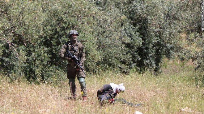 Cảnh tượng kinh hoàng: 4 lính Israel vây bắt, nã đạn vào thiếu niên Palestine bị bịt mắt, còng tay - Ảnh 1.