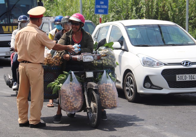 Công an Cần Thơ phát nước suối, khăn lạnh cho người dân lưu thông trên quốc lộ  - Ảnh 3.