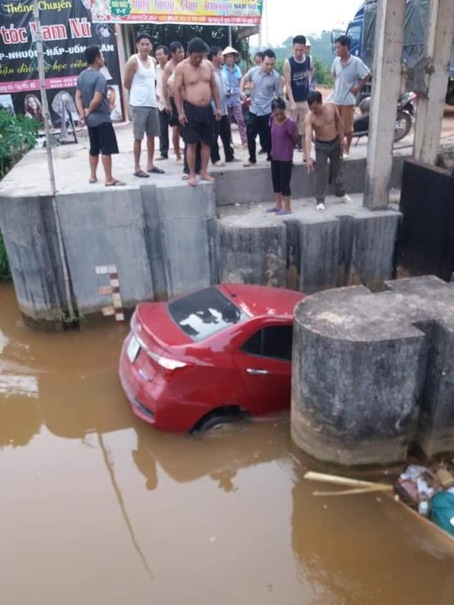 Ô tô màu đỏ nằm dưới mương, rác thải vây xung quanh khiến nhiều người tò mò - Ảnh 1.