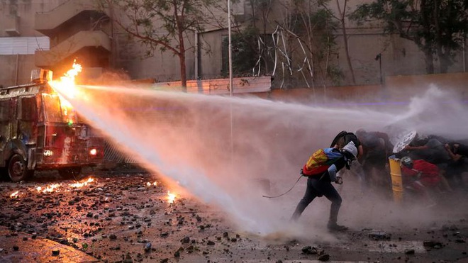 24h qua ảnh: Người biểu tình Chile chống chọi với vòi rồng cảnh sát - Ảnh 3.