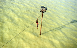 TG 24h qua ảnh: Nam thanh niên 'vắt vẻo' đu dây điện tránh nước lũ