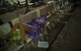Người phụ nữ mặc áo mưa, ngủ qua đêm trên ghế đá chờ xin ấn đền Trần