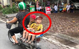 Hai đứa bé ngồi sau yên xe máy trên đường, một chi tiết khiến dân mạng chú ý