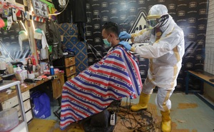 24h qua ảnh: Thợ cắt tóc mặc trang phục bảo hộ kín mít khi phục vụ khách