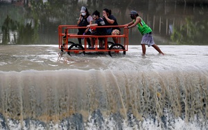24h qua ảnh: Người đàn ông đẩy xe chở khách qua dòng nước lũ ở Philippines