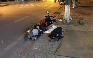 Đang đi đường, thanh niên áo trắng bỗng bỏ xe máy rồi lên vìa hè nằm... ngủ