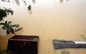 24h qua ảnh: Nông dân chèo thuyền trên nước lụt ngập mái nhà