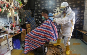 24h qua ảnh: Thợ cắt tóc mặc trang phục bảo hộ kín mít khi phục vụ khách