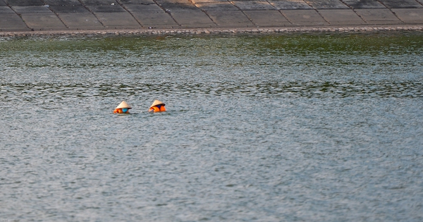 thumbnail - Giữa trời nắng chang chang, bất chấp biển cấm, người dân đội nón bơi ra giữa hồ Linh Đàm