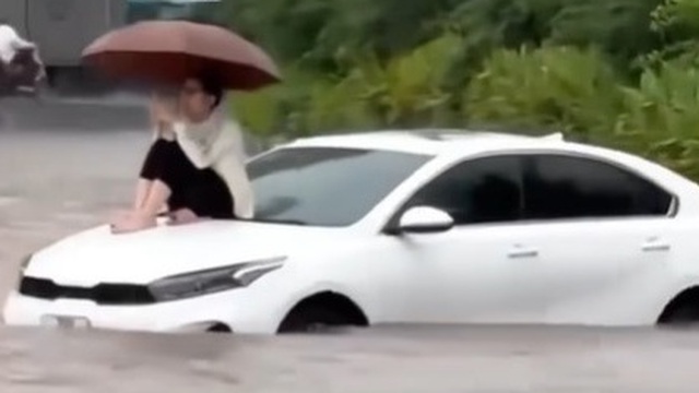 Đường Hà Nội có nơi ngập gần 1m trong sáng nay, người dân ngồi lên nóc xe chờ nước rút