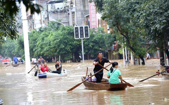 Lũ lụt dâng cao, người dân chèo thuyền đi lại trên phố