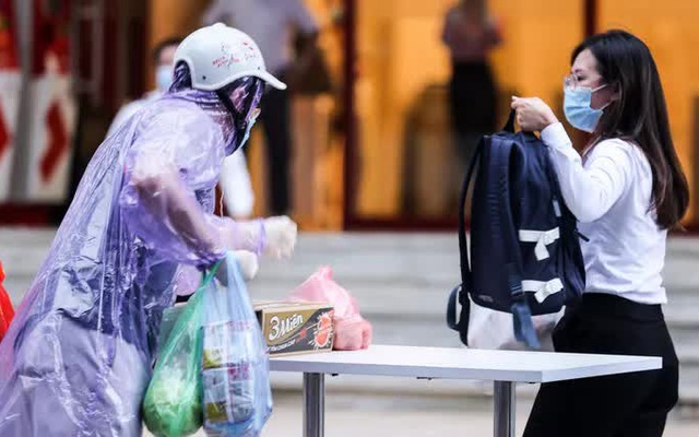 Người dân mặc áo mưa tiếp tế lương thực vào trung tâm thương mại bị phong toả