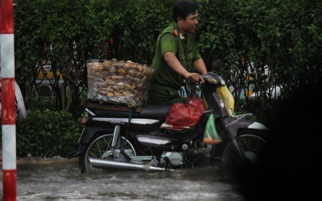 Cảnh sát, công an lội giữa dòng nước ngập sâu dắt xe giúp dân