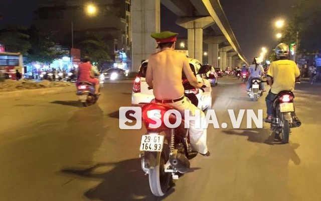 Người đàn ông cởi trần đi xe máy đội mũ cảnh sát diễu phố