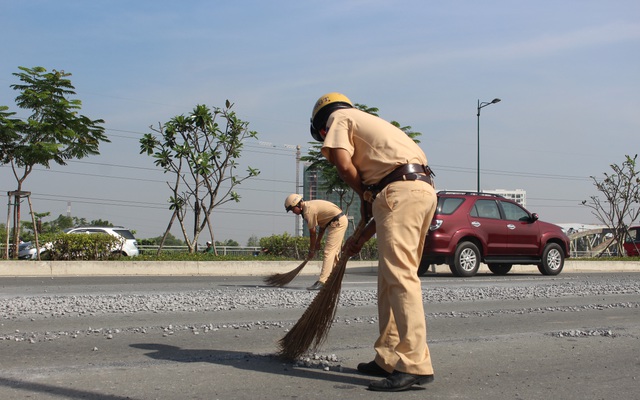 Cảnh sát giao thông đội nắng quét đá rơi vãi trên đường ở Sài Gòn